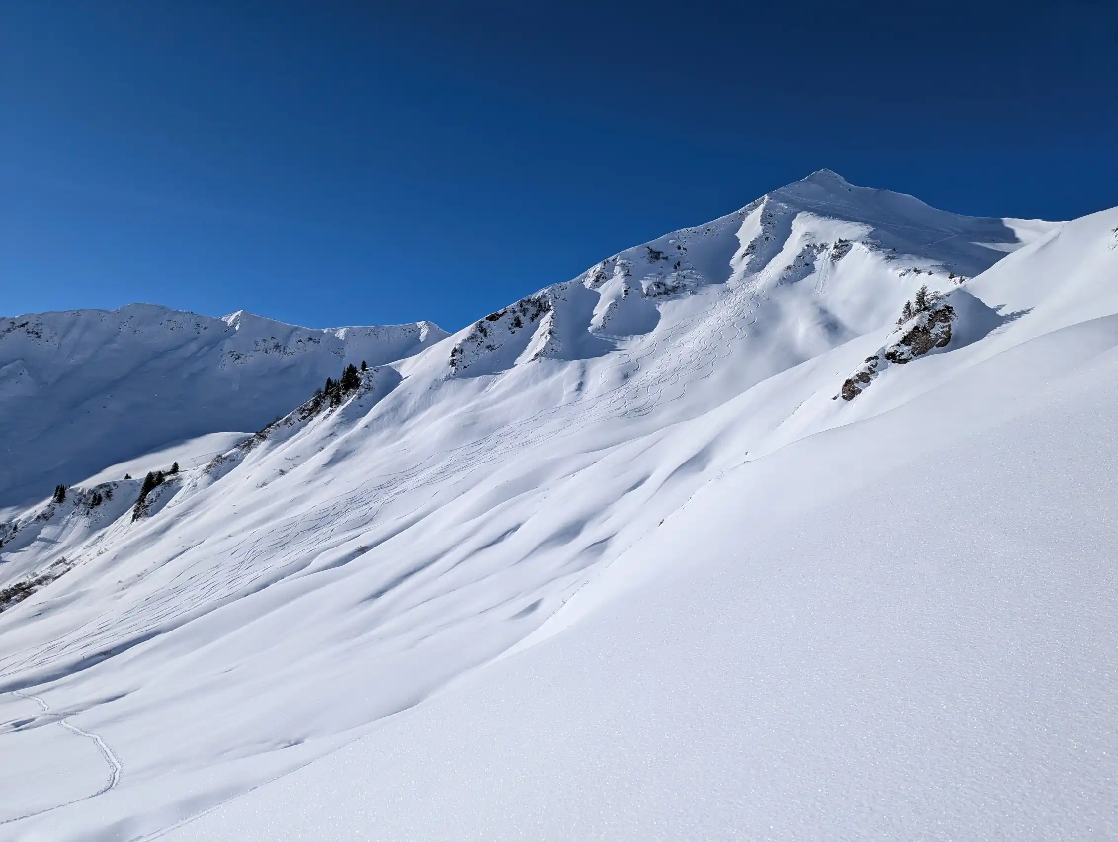 Weite Schneeflächen bedecken die Berghänge von Mittelberg. Die Gipfel sind mit frischem Schnee bedeckt und zeigen deutliche Spuren von Schneefall.